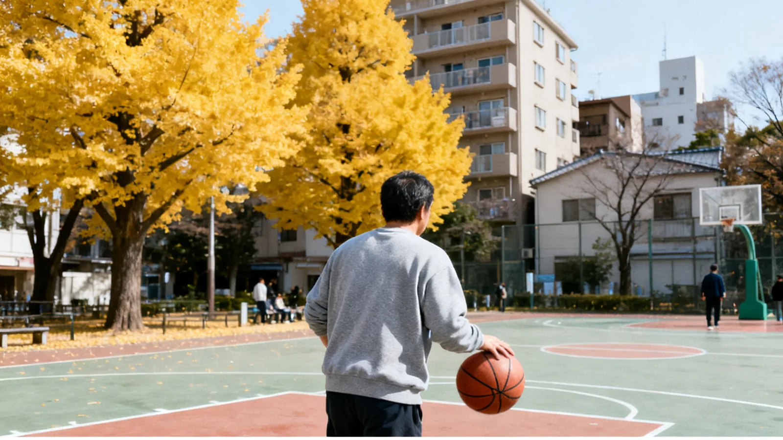 秋の朝、公園のコートで一人バスケットボールをする男性