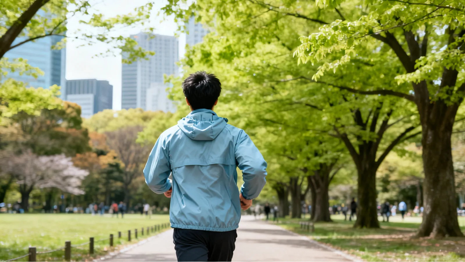 春の朝、公園の道を走る男性の後ろ姿