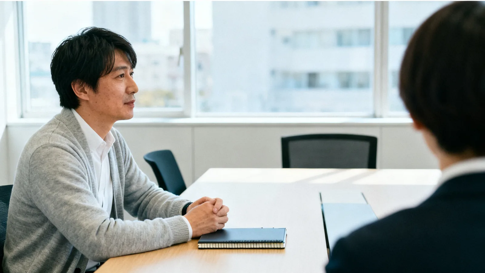 会議の席で同僚の話を最後まで聞く男性
